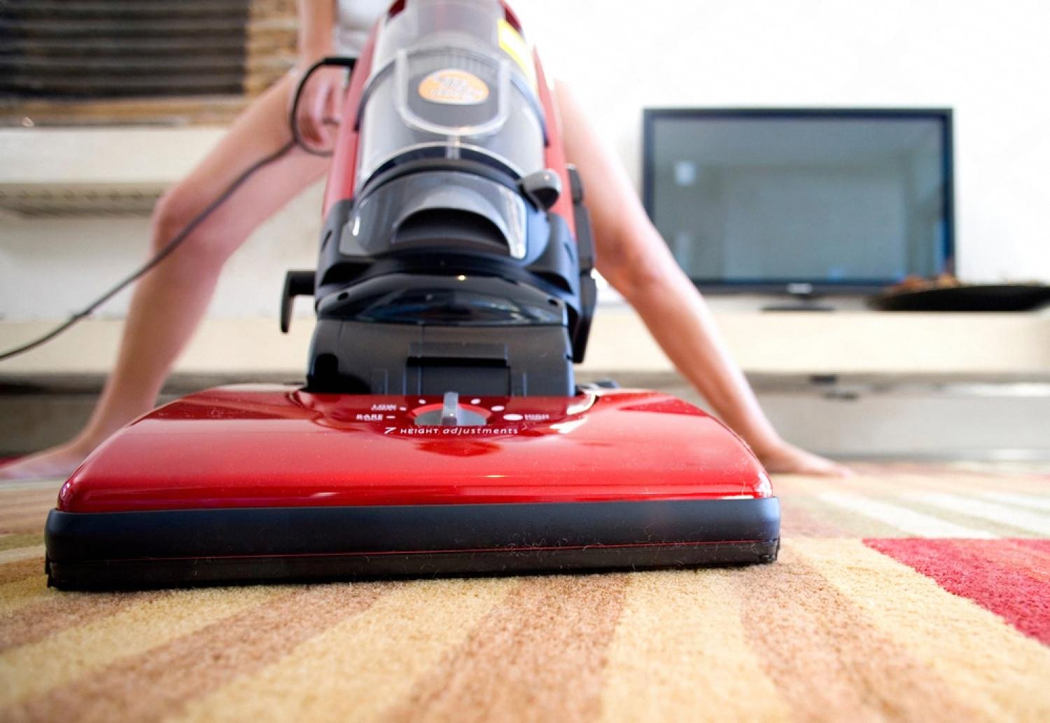 Close-up of an upright vacuum cleaner working across a carpet at pile level